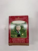 Photo of the Linus Hallmark Keepsake Ornament box showing front with red holiday design, product name, and series info