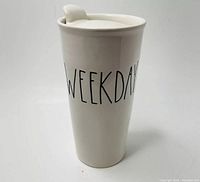 Photo of the white ceramic Rae Dunn tumbler with the word WEEKDAY printed in black text on the side, showing front view.