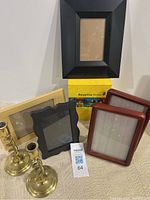 Full lot showing two brass candlesticks, five picture frames in various colors and materials, and the Rosetta Stone Spanish software box.