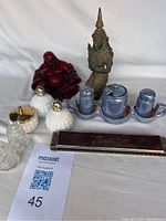 Overview photo showing all items in the lot including salt and pepper sets, harmonica, cut glass pieces, and Buddha statues