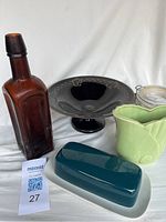 Vintage glass and ceramic items including the brown bottle, amethyst pedestal bowl, green vase, glass jar, and butter dish.