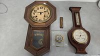 Full lot showing antique Seikosha clock, large and small temperature gauges, and a small alarm clock on a gray surface.