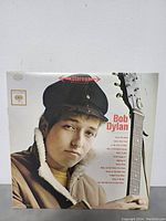 Front cover of Bob Dylan's self-titled LP featuring a young Bob Dylan with guitar.