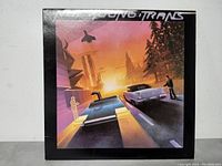 Front cover of Neil Young Trans vinyl LP record album showing futuristic artwork with cars and sunset cityscape.