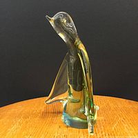 Side angle showing the penguin's extended wing and beak details with subtle green and blue tint in the glass.