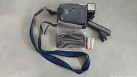 Sony Digital Handycam with attached hand strap, remote control in plastic bag, and two AA batteries.
