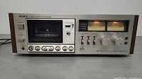 Front view of Sony stereo cassette deck powered on with cassette inside and illuminated VU meters.