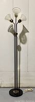 Full view of the vintage floor lamp showing black base, three upright rods, and glass shades with brass fittings.