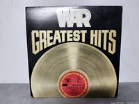 Front cover of War Greatest Hits album showing large gold record illustration and title.