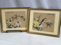 Two framed traditional Chinese bird prints with floral backgrounds, gold-tone frames, one frame shows scuffs.
