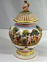 Front view of the covered jar showing angel on lid and cherubs harvesting around the body