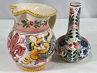 Photo showing smaller ceramic pitcher with colorful hand painted floral and bird motifs, white base with yellow trim on rim and handle.