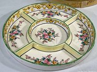 Angle view of entire round divided plate with floral hand-painted decoration and five sections.