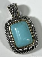 Front-facing close-up of the turquoise stone set in twisted rope design sterling silver frame and bail.
