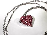 Close-up of pink heart-shaped Swarovski crystal pendant on silver tone chain.