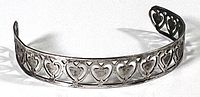Front angled view of the open cuff bracelet showing repeating heart design in sterling silver.