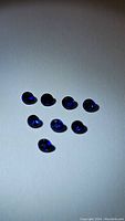 Nine natural Ceylon royal blue sapphires displayed on white background, showing rich blue color and small round cabochon shape.