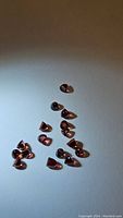 Multiple almandine garnet gemstones with fancy bullet cut, orange-red color, and VS-VVS clarity on a white surface.