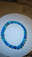 Full view of the blue agate round bead bracelet placed on light background showing color and bead pattern.