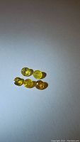 Six round cut canary yellow sapphire gemstones displayed on white background to show size, shape and color.