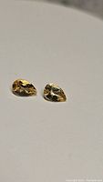 Two pear cut golden citrine gemstones on white background, showing clarity and color.