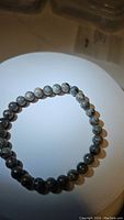 Yooperlite bracelet displayed on a round white surface with visible round gray-black beads showing natural patterns.