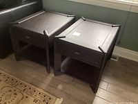 Two black wooden end tables side by side, showing their overall design, color, and condition.
