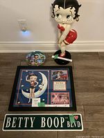 All four Betty Boop items together: figurine, collector plate, framed collage, tin sign