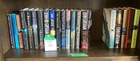Photo of the set of John Grisham hardcover and paperback novels lined up on a shelf, titles clear on spines.