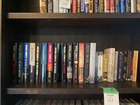 Shelf with hardcover and paperback books by Jeffrey Archer and Michael Connelly sorted with spines facing outward showing titles and authors.