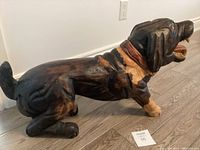 Side view of the wooden dog carving, showing detailed coloring and pose.