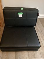 Photo of black folding chair in chair form showing stitched square pattern on seat and backrest.