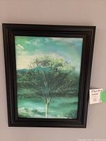 Front view of lenticular framed tree print showing one seasonal image of the tree with green foliage and a partly cloudy sky.
