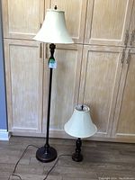 Photo showing full view of floor lamp and table lamp with white bell-shaped shades and polished brass bases.