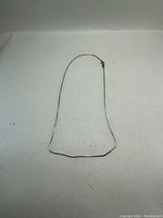 Image of a thin sterling silver chain necklace laid out flat on a white background.