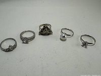 Photo showing the five costume jewelry rings arranged in a row on a plain surface.