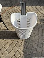 Top/front view of the white plastic laundry hamper with ventilation holes and extended handle
