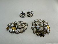 Photo of vintage brooches and clip-on earrings showing white, off-white, and iridescent marquise stones, some stones missing on brooches as noted.
