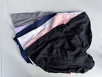 Six pairs of women's underwear in various colors laid out fan style on flat surface.