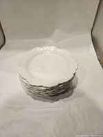 Stack of six white Wedgwood cabbage leaf patterned salad plates showing embossed leaf details and scalloped edges.