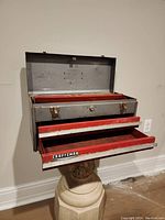 Open front view showing 2 red pull-out drawers and open lid compartment lined in red.