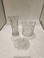 Front view of two crystal vases and a detached lid showing overall condition and design patterns