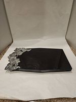 Black marble cheese board with silver grapevine corner highlight shown on white background.