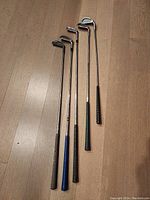 Five irons (3,4,5,7,8) lined up on floor showing various colored grips
