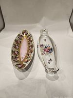 Two handpainted porcelain serving dishes seen from the top showing floral designs and gold accents.