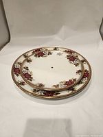 Two stacked ceramic cake stand plates showing floral pattern and central holes for stand poles.