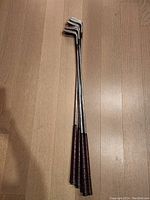 Four Top Flight Synchro-dyned irons laid together, clubs showing from grip to club head, shot vertically from above on wooden floor.