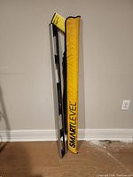 Photo showing the 48-inch electronic auto level next to its yellow padded carry case with black 'SMARTLEVEL' text.