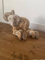 Side view of the largest elephant figurine in the collection showing trunk up and textured shell/seed pod covering over the body.