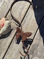 Rusty metal butterfly hanger with clip hook, taken outdoors on wooden surface